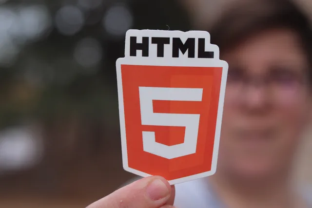 A close-up of an HTML5 logo sticker held by a person with a blurred background, highlighting web development. How UK agencies can shortlist an HTML5 ad builder